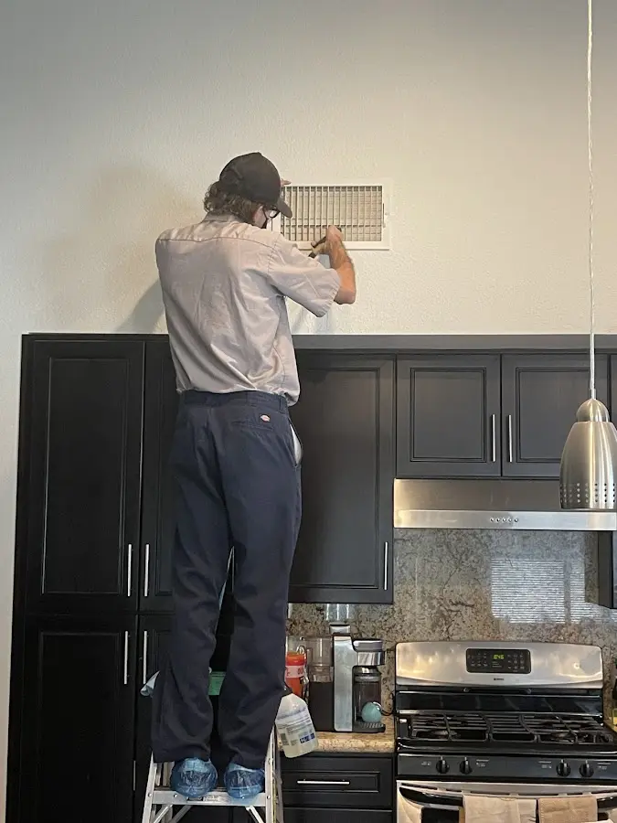 Technician inspecting an air vent during HVAC service in Gateway